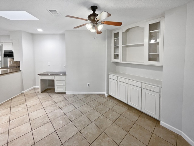 interior space with light tile patterned flooring, a skylight, and visible vents