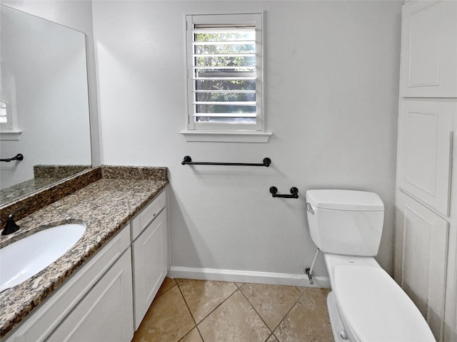 bathroom featuring tile patterned flooring, vanity, toilet, and baseboards