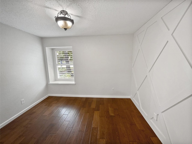 empty room with wood-type flooring, a textured ceiling, and baseboards