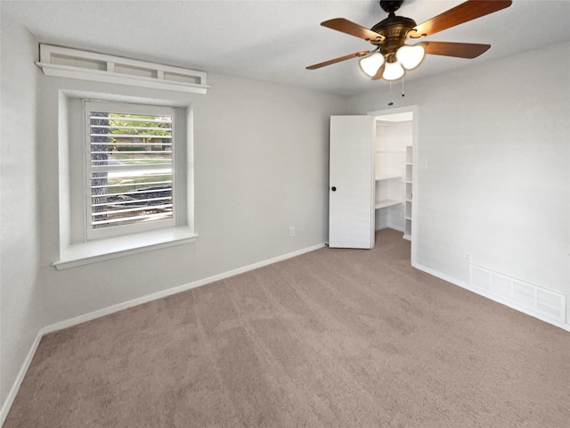 carpeted spare room featuring ceiling fan, visible vents, and baseboards