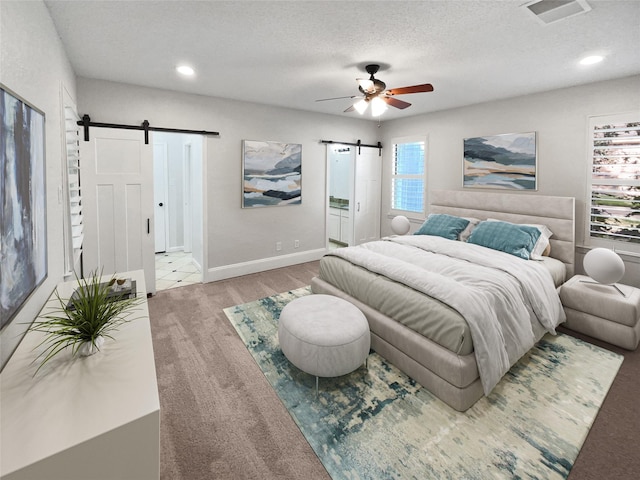 bedroom featuring recessed lighting, visible vents, a barn door, ceiling fan, and a textured ceiling