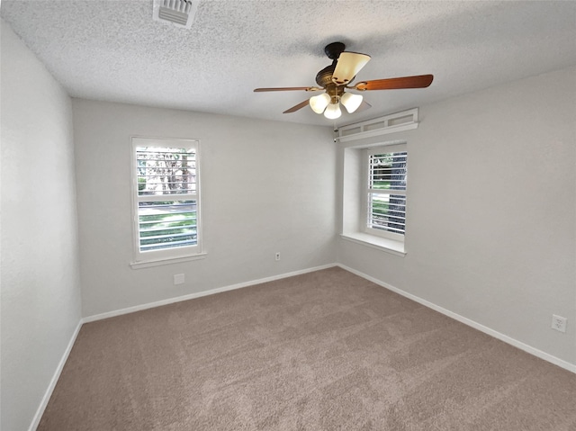 unfurnished room featuring a wealth of natural light, carpet, visible vents, and baseboards