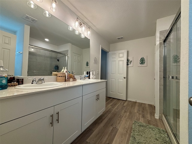 bathroom featuring vanity, a textured ceiling, hardwood / wood-style floors, and a shower with shower door