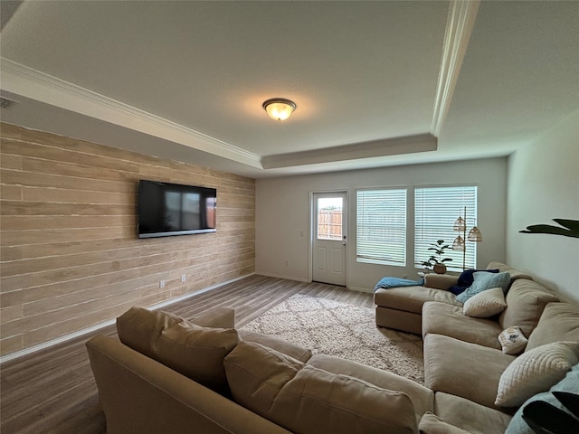 living room featuring a tray ceiling, hardwood / wood-style flooring, and ornamental molding