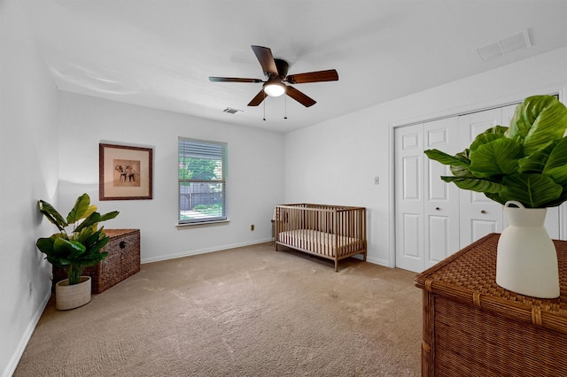 carpeted bedroom featuring a closet, ceiling fan, and a nursery area