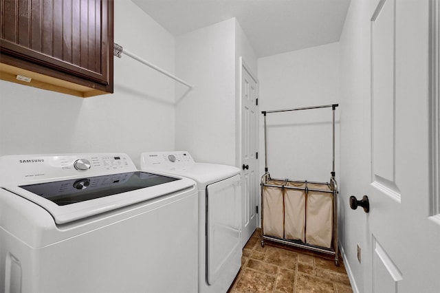 washroom featuring cabinet space, stone finish floor, and washer and clothes dryer