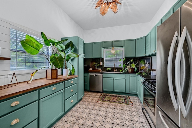 kitchen with decorative backsplash, green cabinetry, butcher block counters, appliances with stainless steel finishes, and a sink