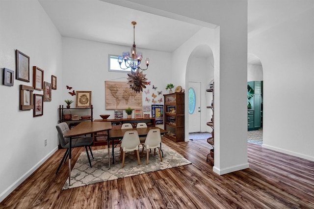 dining area featuring arched walkways, dark wood-style flooring, and a notable chandelier