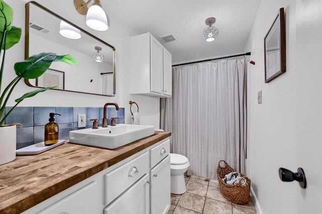 bathroom with tile patterned floors, walk in shower, toilet, decorative backsplash, and vanity