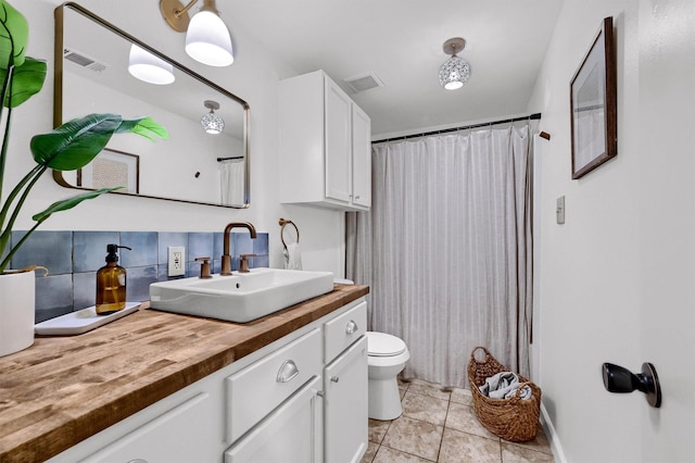 bathroom featuring toilet, vanity, visible vents, and tile patterned floors