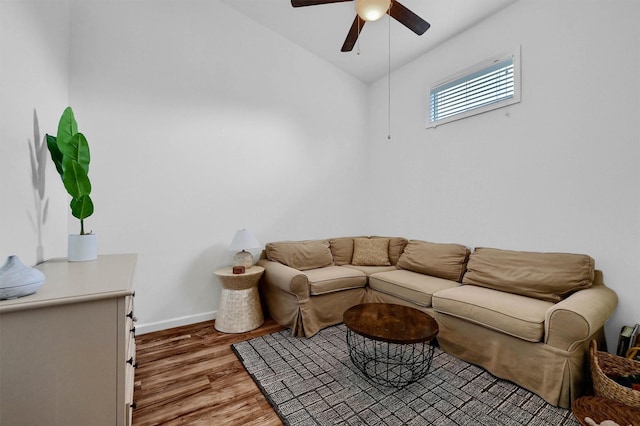 living area featuring ceiling fan, baseboards, vaulted ceiling, and wood finished floors