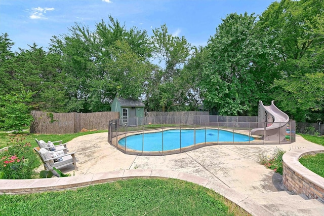 view of swimming pool featuring a fenced in pool, a patio area, a water slide, a fenced backyard, and an outdoor structure