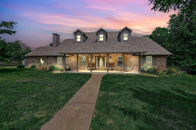 view of front facade with a front lawn, a shingled roof, and brick siding