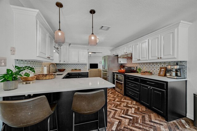 kitchen with decorative light fixtures, backsplash, kitchen peninsula, stainless steel appliances, and white cabinets