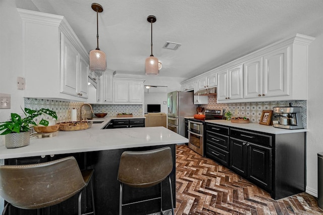 kitchen featuring dark cabinets, stainless steel appliances, a peninsula, visible vents, and white cabinetry