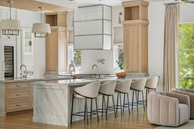 kitchen featuring light wood-type flooring, light brown cabinets, and a kitchen bar