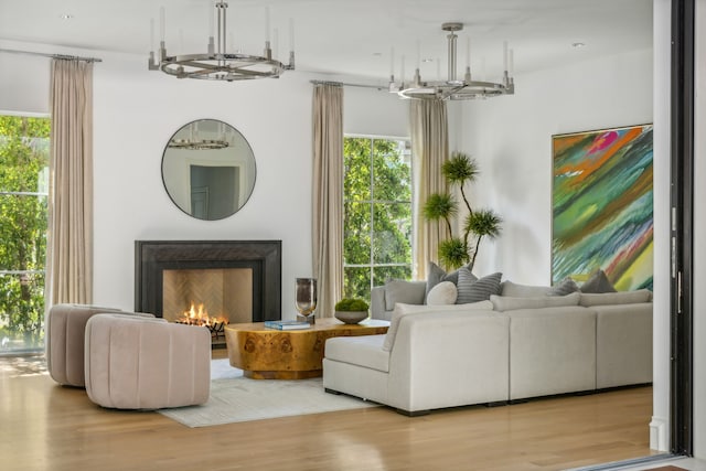 living room with a wealth of natural light, an inviting chandelier, and light hardwood / wood-style floors