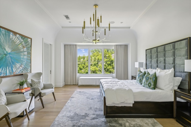 bedroom with ornamental molding, an inviting chandelier, and light hardwood / wood-style flooring