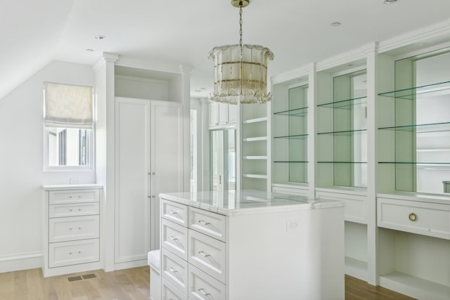 spacious closet featuring lofted ceiling, a notable chandelier, and light hardwood / wood-style floors