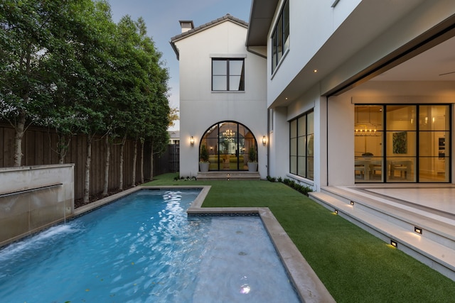 view of pool with pool water feature and a lawn