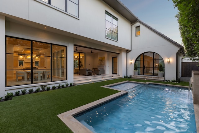 back house at dusk with a yard, pool water feature, a fenced in pool, and a patio area