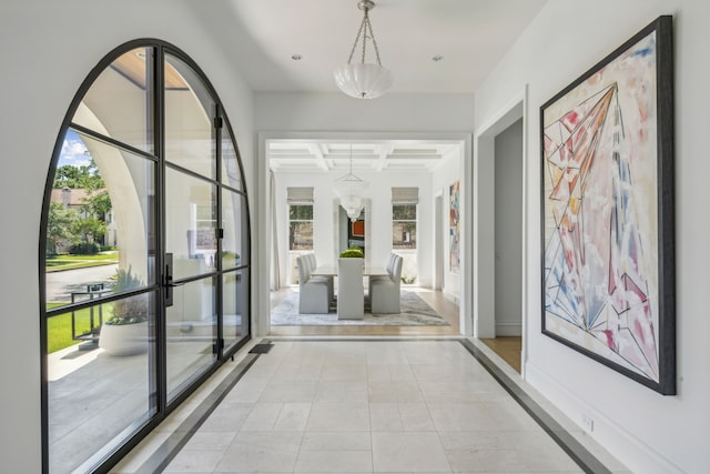 hall with coffered ceiling, plenty of natural light, light tile patterned flooring, and beamed ceiling