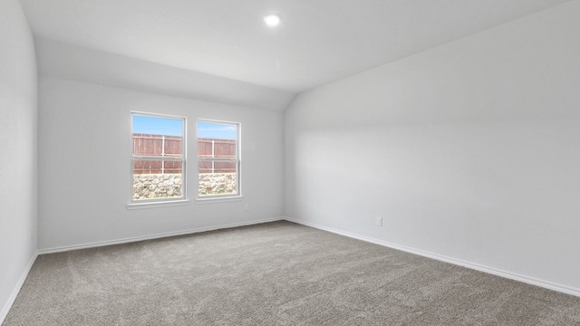 carpeted spare room featuring vaulted ceiling