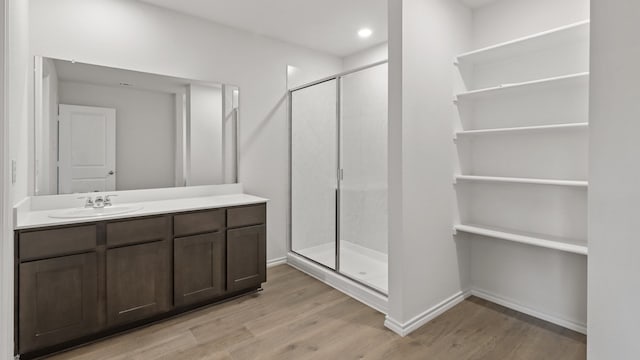 bathroom with hardwood / wood-style floors, walk in shower, and vanity