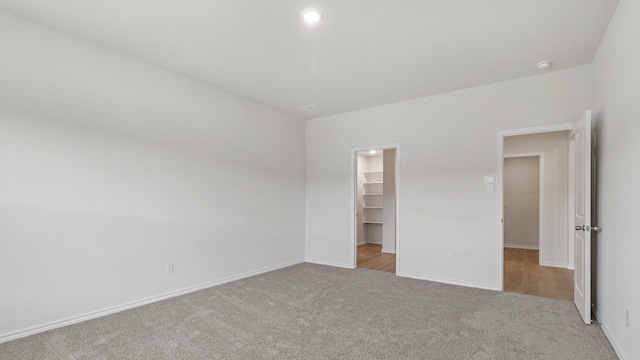 unfurnished bedroom featuring light carpet, a closet, and a walk in closet