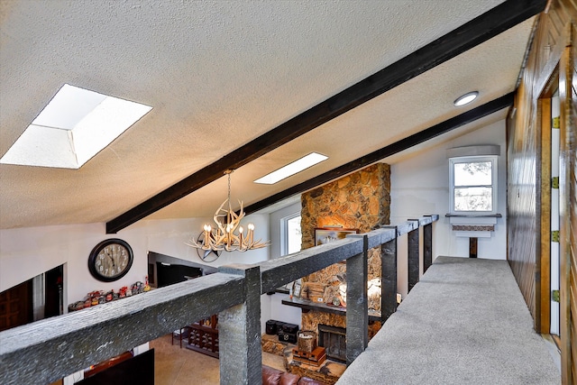 hall featuring an inviting chandelier, lofted ceiling with skylight, and a textured ceiling