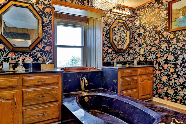 bathroom featuring a bath, a textured ceiling, and vanity