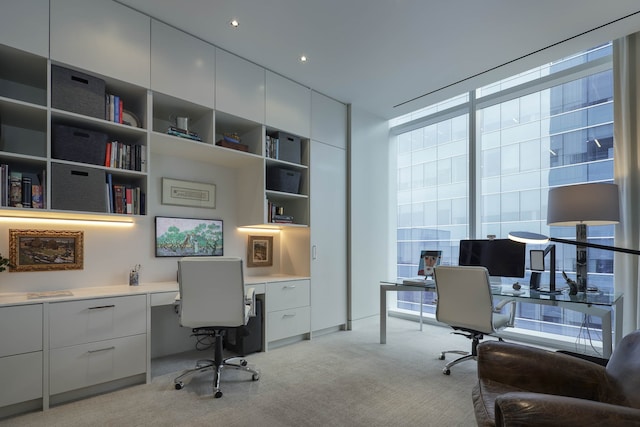 office area with built in shelves, built in desk, light carpet, and floor to ceiling windows