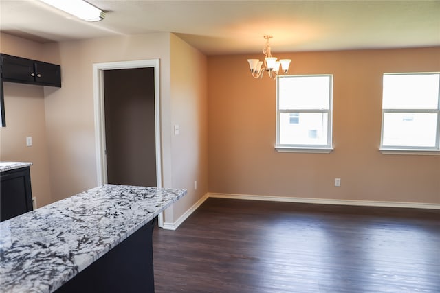 kitchen featuring hanging light fixtures, light stone countertops, a notable chandelier, and dark hardwood / wood-style floors