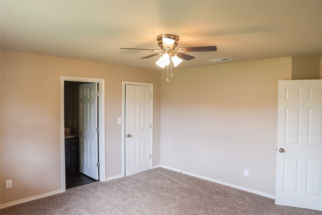 unfurnished bedroom featuring carpet, ceiling fan, and ensuite bath