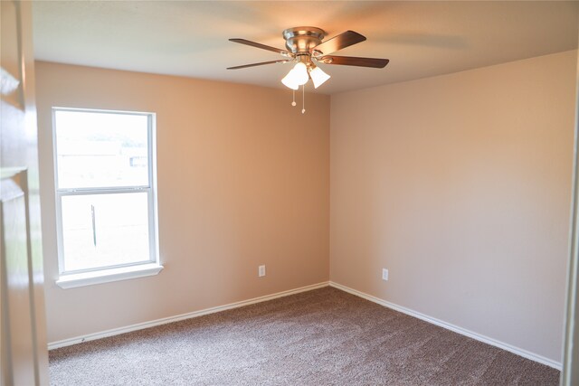 carpeted spare room featuring a wealth of natural light and ceiling fan