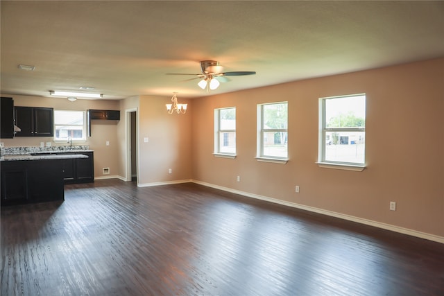 unfurnished living room with ceiling fan with notable chandelier and dark hardwood / wood-style flooring