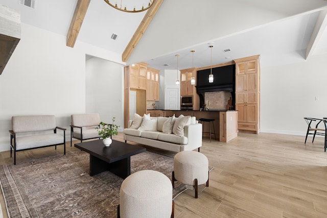 living room with sink, high vaulted ceiling, beam ceiling, and light hardwood / wood-style flooring