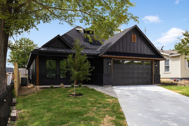 view of front of home featuring a garage, a front yard, and central AC unit