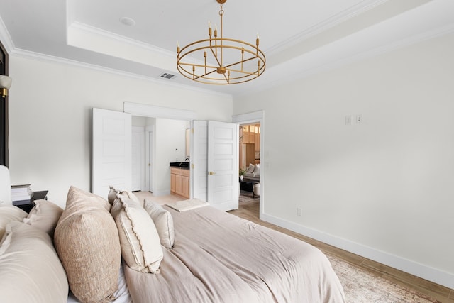 bedroom featuring a tray ceiling, ornamental molding, an inviting chandelier, and light hardwood / wood-style floors