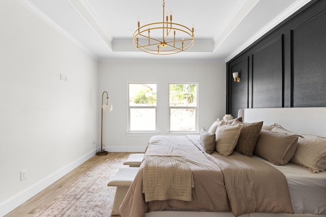 bedroom with ornamental molding, a raised ceiling, light hardwood / wood-style flooring, and an inviting chandelier