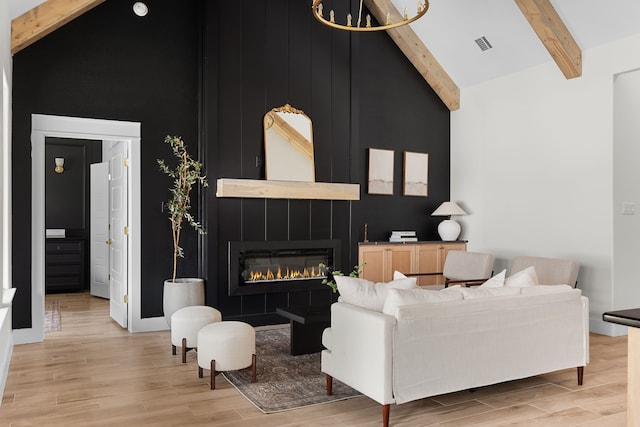 living room with high vaulted ceiling, a tile fireplace, light hardwood / wood-style floors, and beamed ceiling