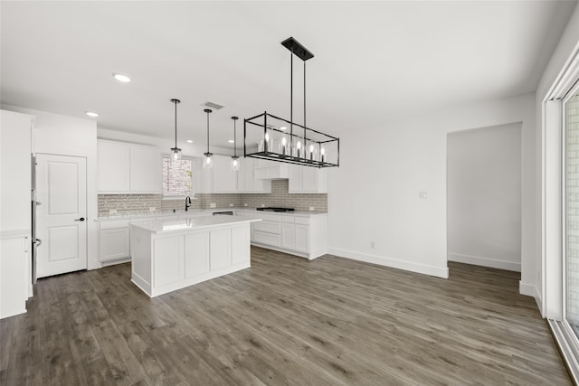 kitchen featuring white cabinets, decorative light fixtures, dark wood-type flooring, black gas stovetop, and a center island