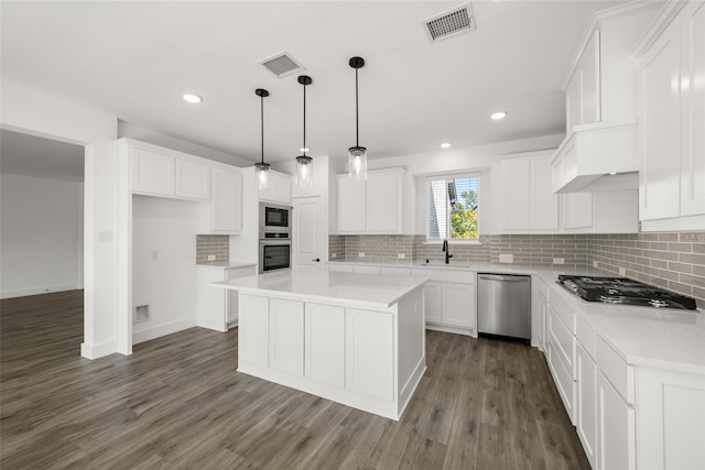 kitchen with a center island, dark wood-type flooring, white cabinets, appliances with stainless steel finishes, and decorative light fixtures