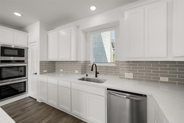 kitchen featuring tasteful backsplash, dark wood-type flooring, sink, white cabinets, and stainless steel appliances