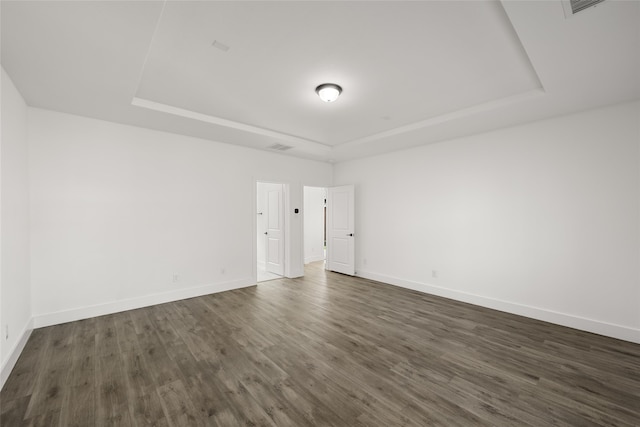 unfurnished room featuring a tray ceiling and dark wood-type flooring