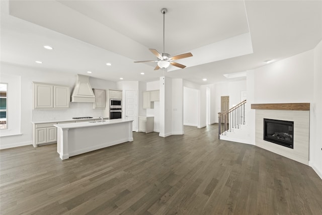 unfurnished living room featuring ceiling fan, dark hardwood / wood-style floors, a tiled fireplace, and sink