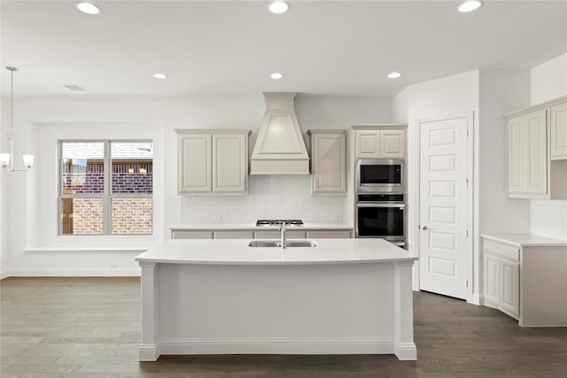 kitchen with decorative light fixtures, decorative backsplash, dark wood-type flooring, stainless steel appliances, and custom range hood