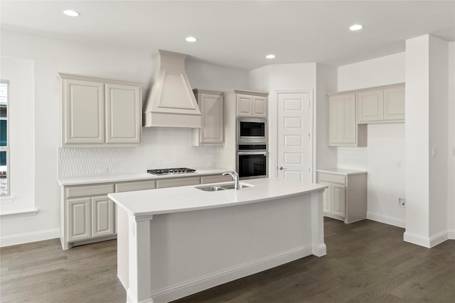 kitchen featuring sink, custom exhaust hood, appliances with stainless steel finishes, dark hardwood / wood-style flooring, and a kitchen island with sink