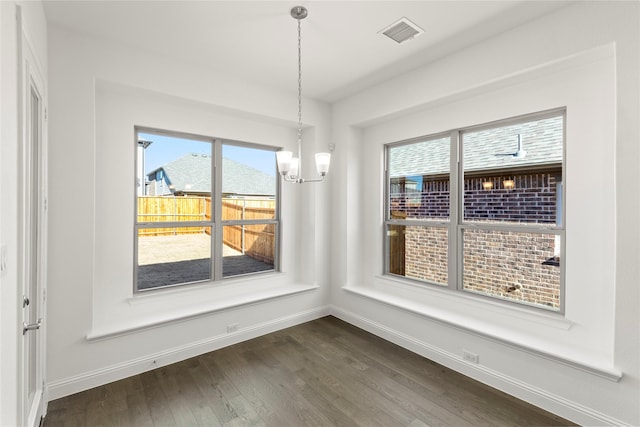 unfurnished dining area featuring dark hardwood / wood-style floors and an inviting chandelier