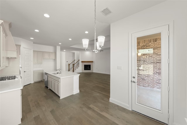 kitchen featuring sink, white cabinetry, pendant lighting, stainless steel appliances, and a kitchen island with sink